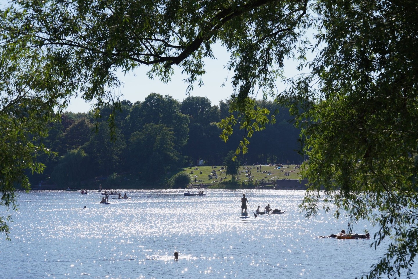 Menschen paddeln in der Sonne auf dem Hamburger Stadtparksee.