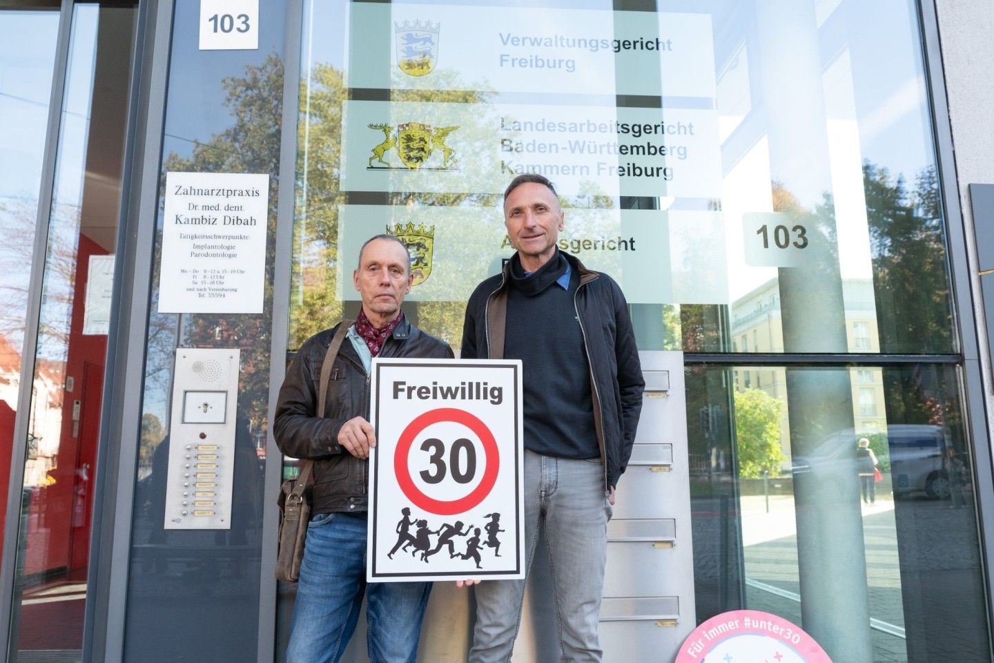 Christian Kronbitter (l) und Erich Maier vor dem Verwaltungsgericht in Freiburg mit einem «Freiwillig 30»-Schild.