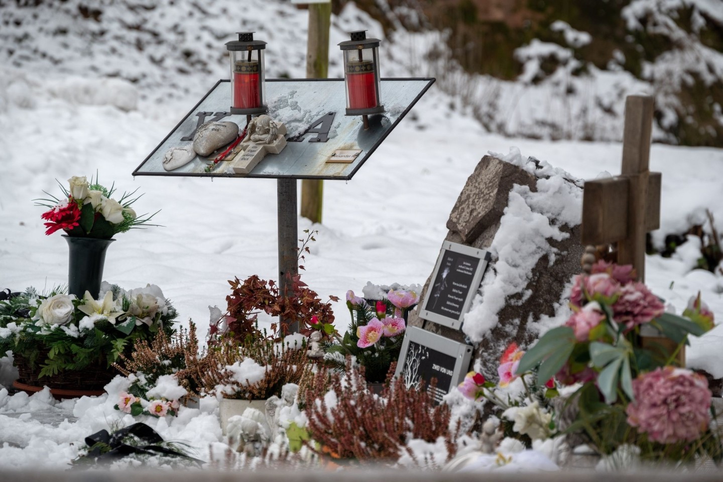 Ein Gedenkstein, eine Gedenktafel, Engelfiguren und Blumen erinnern auf einem Parkplatz bei Kusel an die beiden Polizisten, die vor einem Jahr im Dienst getötet wurden.